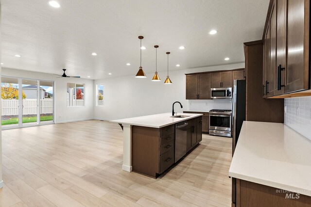 kitchen featuring decorative backsplash, an island with sink, dark brown cabinetry, and stainless steel appliances
