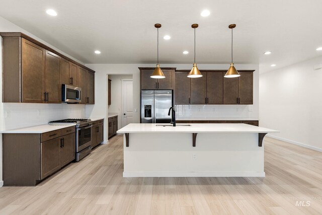 kitchen featuring a sink, dark brown cabinets, appliances with stainless steel finishes, and light wood-style floors