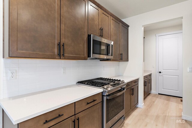 kitchen with tasteful backsplash, dark brown cabinetry, light countertops, light wood-style floors, and stainless steel appliances