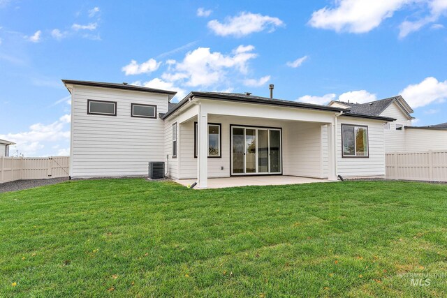 rear view of property with central air condition unit, a patio, a fenced backyard, and a lawn