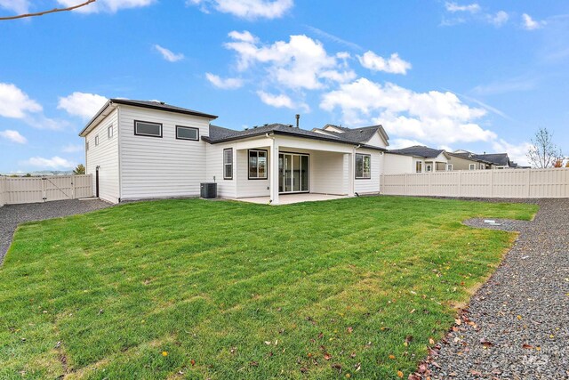 rear view of property featuring cooling unit, a patio area, a fenced backyard, a yard, and a gate