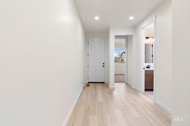 hall with light wood-style flooring, baseboards, and recessed lighting