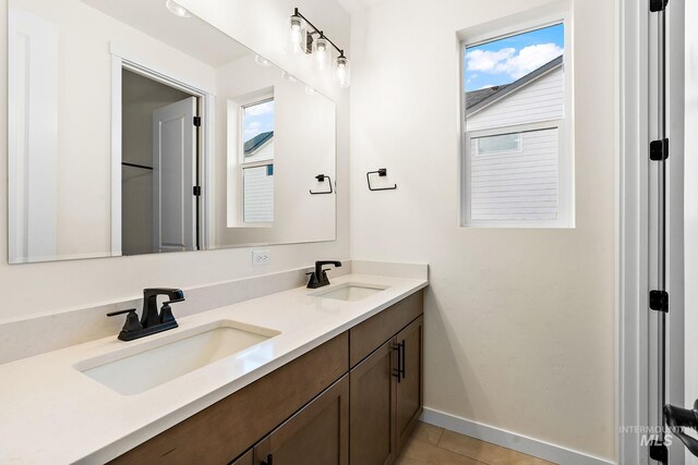 bathroom featuring tile patterned floors, double vanity, a sink, and baseboards