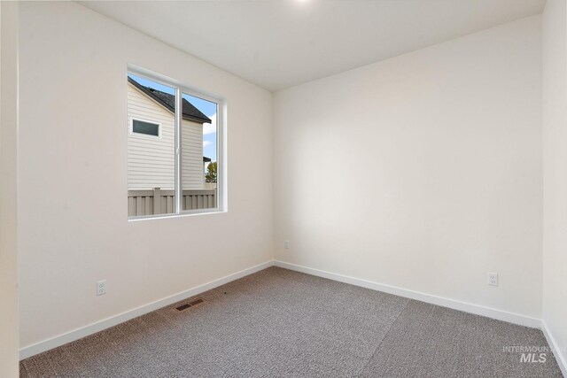unfurnished room with carpet flooring, visible vents, and baseboards