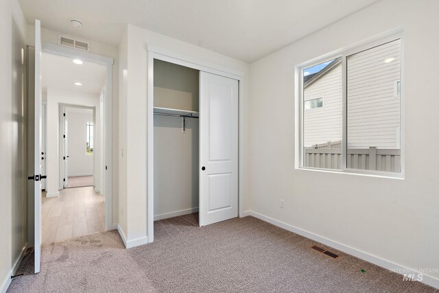 unfurnished bedroom with visible vents, baseboards, and light colored carpet