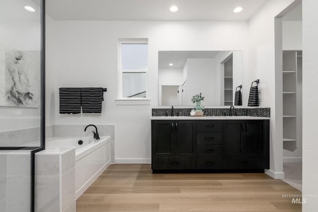 bathroom with wood-type flooring, a bathing tub, and vanity