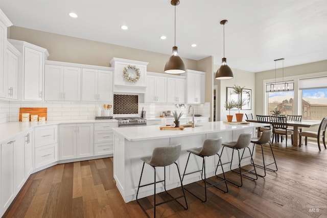 129 E 33 S, Burley, ID 83318 - kitchen featuring dark wood-style floors, white cabinets, an island with sink, and a kitchen bar