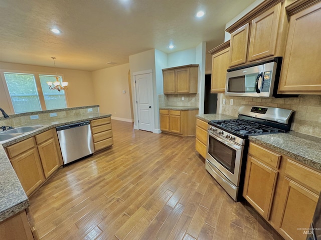 2577 Longbow Dr, Twin Falls, ID 83301 - kitchen featuring appliances with stainless steel finishes, a chandelier, light wood-type flooring, tasteful backsplash, and recessed lighting