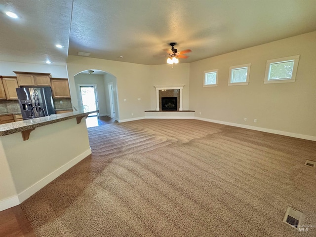 2577 Longbow Dr, Twin Falls, ID 83301 - unfurnished living room featuring a ceiling fan, arched walkways, carpet, a fireplace with raised hearth, and recessed lighting