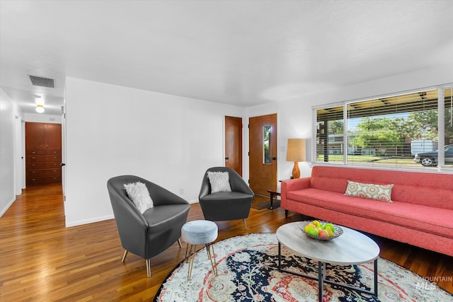 living room with visible vents, baseboards, and wood finished floors