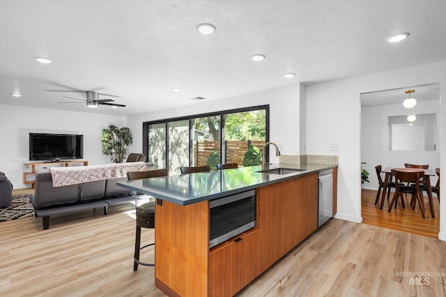 kitchen with light wood finished floors, stainless steel appliances, a breakfast bar, and a sink