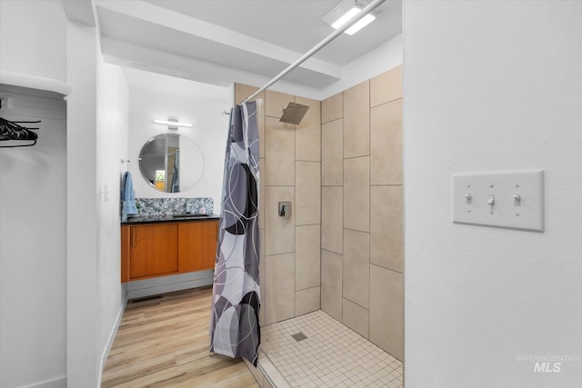 bathroom featuring wood finished floors, vanity, and a tile shower