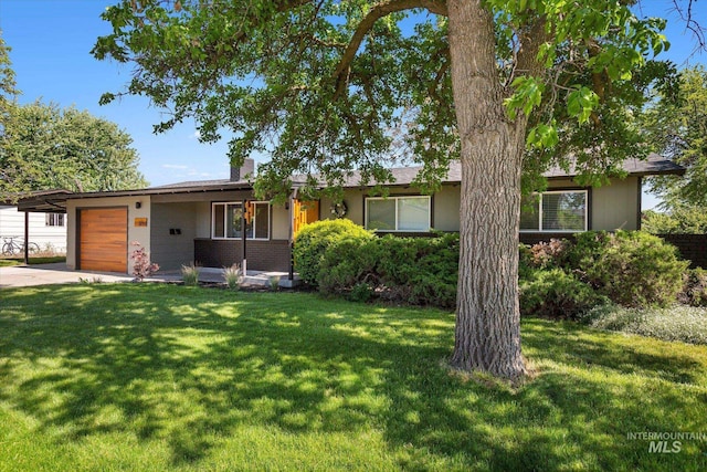 single story home featuring an attached garage, a chimney, a front lawn, concrete driveway, and brick siding