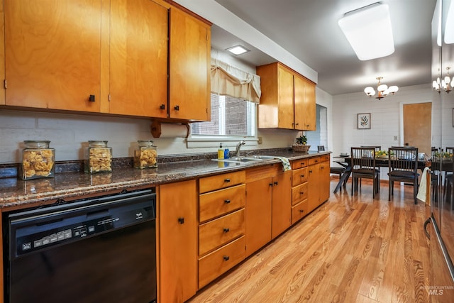 kitchen featuring sink, light hardwood / wood-style flooring, dark stone countertops, black dishwasher, and a notable chandelier