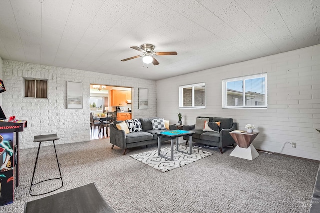 living room featuring carpet, ceiling fan, and brick wall