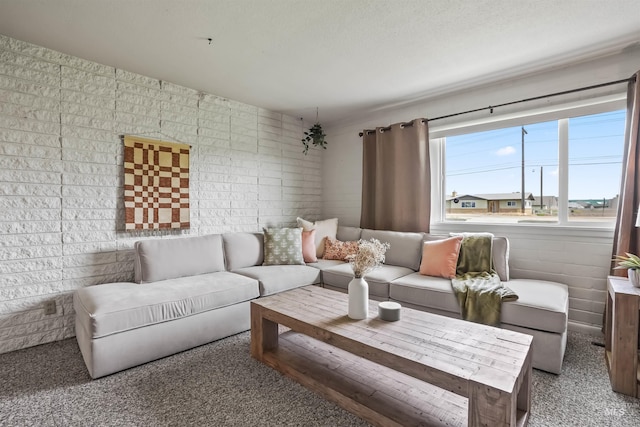 carpeted living room with brick wall