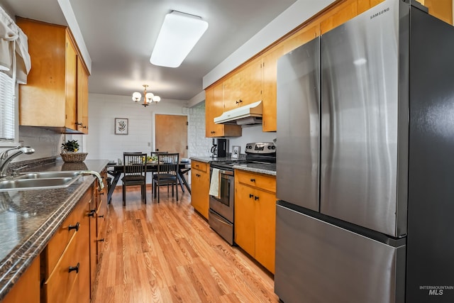 kitchen featuring stainless steel appliances, light hardwood / wood-style flooring, a notable chandelier, and sink