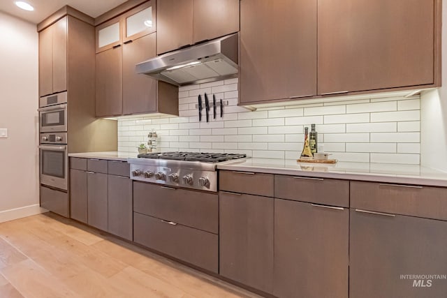 kitchen featuring stainless steel gas cooktop, decorative backsplash, and light wood-type flooring