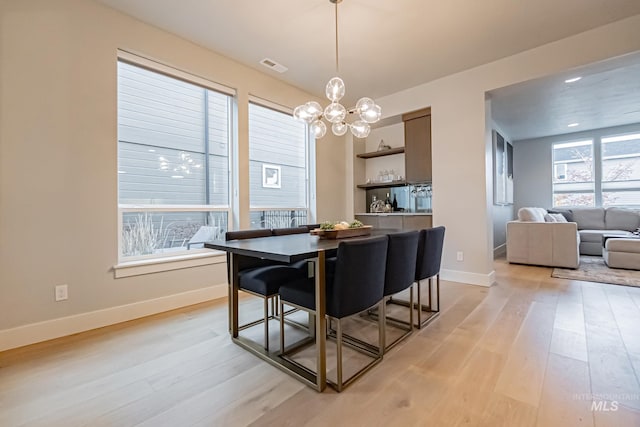 dining room featuring light wood-type flooring and an inviting chandelier