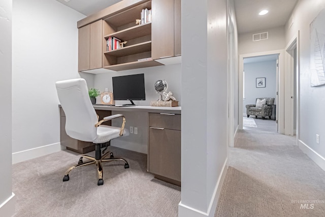 carpeted home office featuring built in desk