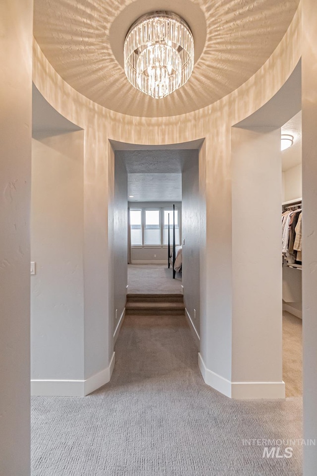 corridor featuring carpet flooring and a chandelier