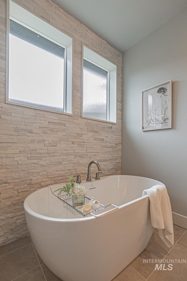 bathroom with tile patterned floors and a bath