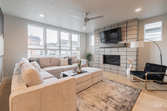 living room featuring a large fireplace, ceiling fan, and hardwood / wood-style floors