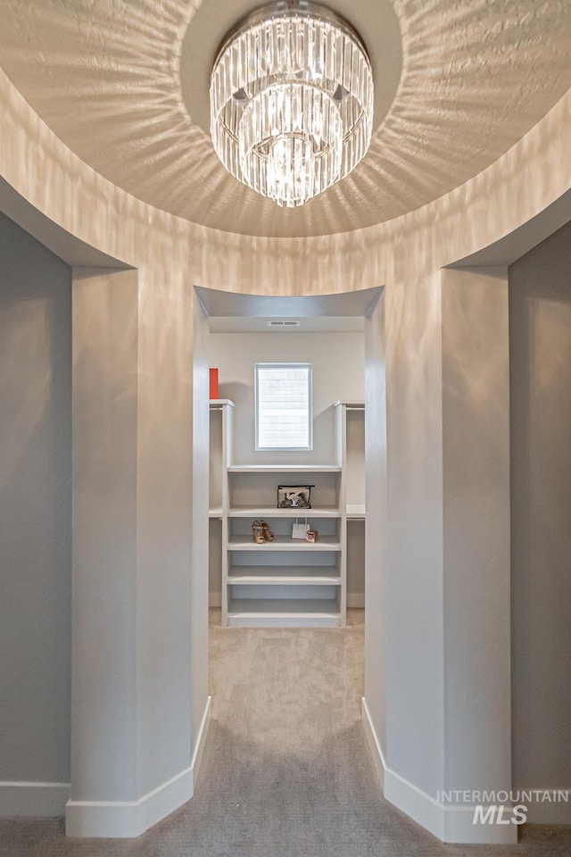 hall with carpet and a notable chandelier