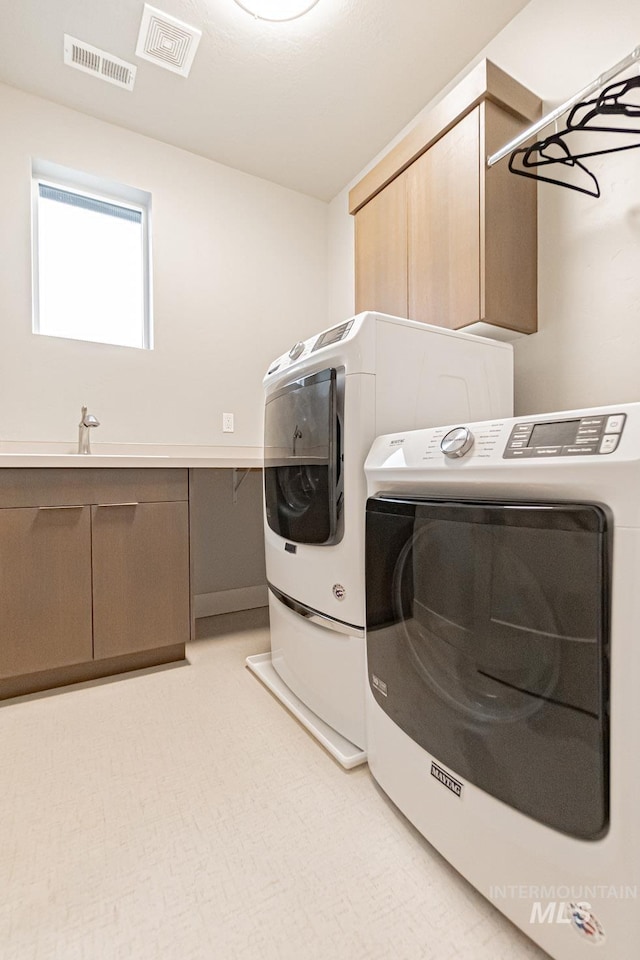 clothes washing area with washer and dryer, cabinets, light colored carpet, and sink