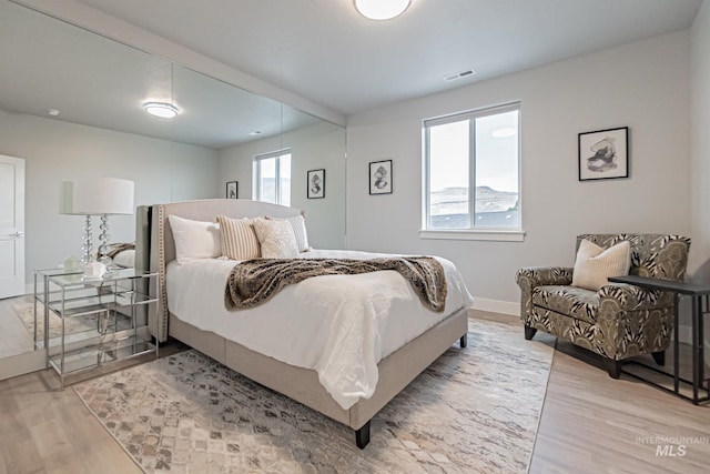 bedroom with light wood-type flooring and multiple windows