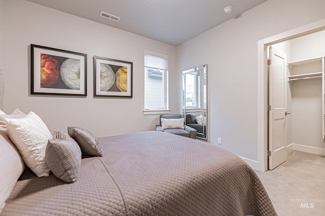 carpeted bedroom featuring a walk in closet and a closet