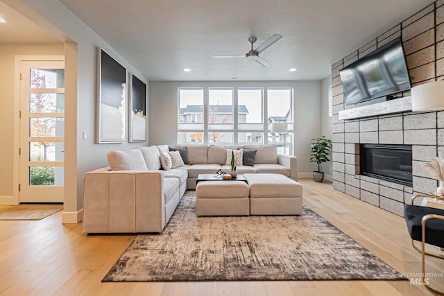 living room with a healthy amount of sunlight, a fireplace, ceiling fan, and light hardwood / wood-style floors