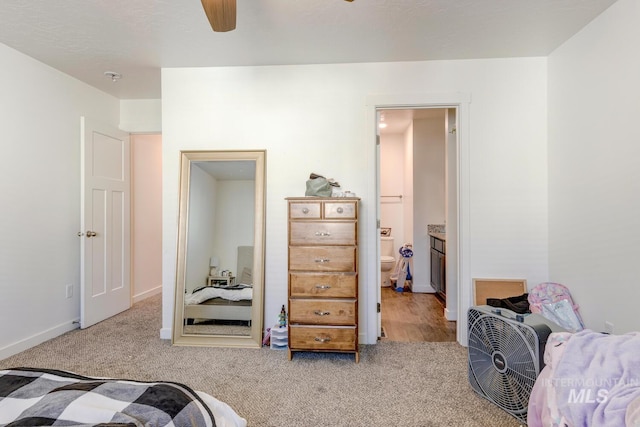 carpeted bedroom with connected bathroom, a ceiling fan, and baseboards