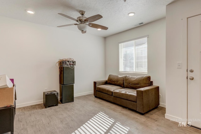 living room featuring light wood-style flooring, baseboards, and visible vents