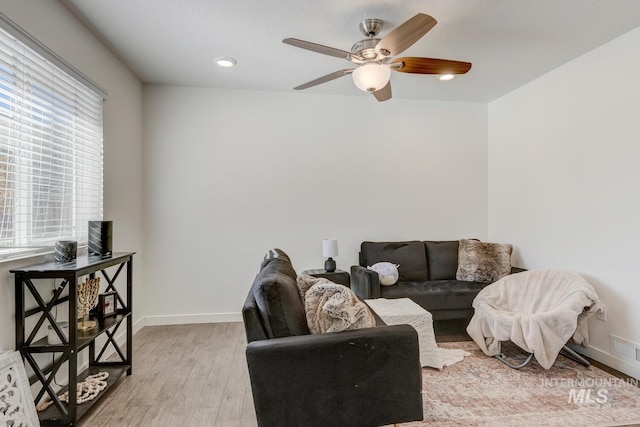 living room with visible vents, baseboards, ceiling fan, and light wood finished floors