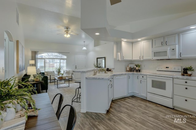 kitchen with light hardwood / wood-style floors, white cabinetry, white appliances, and kitchen peninsula