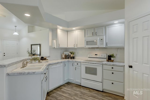 kitchen featuring lofted ceiling, white appliances, kitchen peninsula, hanging light fixtures, and white cabinetry