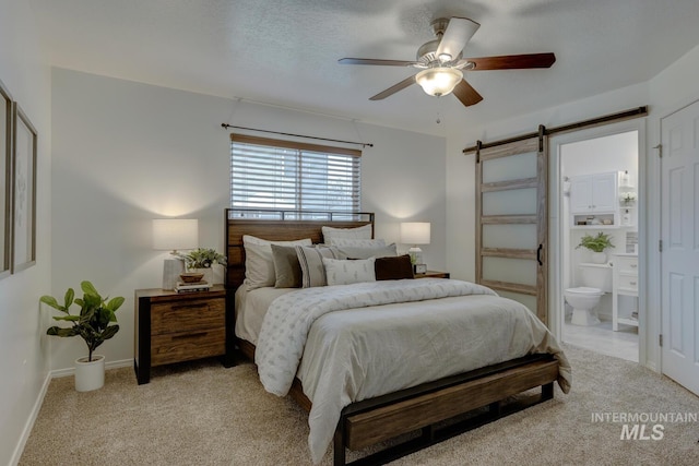 carpeted bedroom featuring ensuite bath, ceiling fan, a textured ceiling, and a barn door