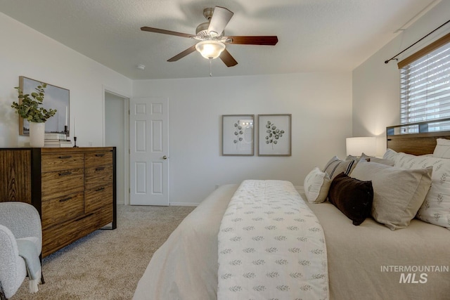 bedroom with ceiling fan, light colored carpet, and a textured ceiling