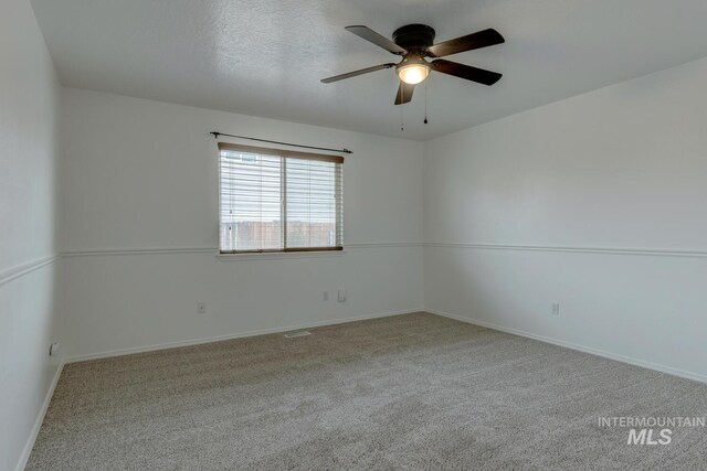 empty room with light carpet, ceiling fan, and a textured ceiling