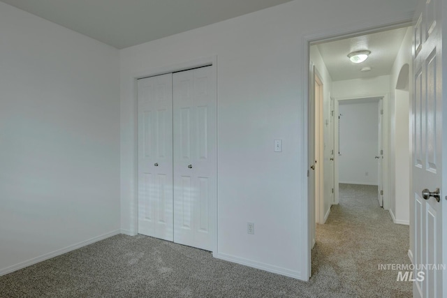 unfurnished bedroom featuring a closet and light colored carpet