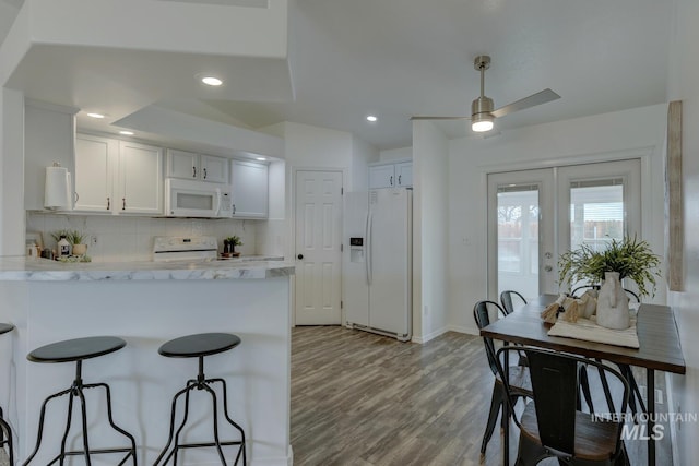 kitchen featuring tasteful backsplash, light stone counters, light hardwood / wood-style flooring, white appliances, and white cabinets