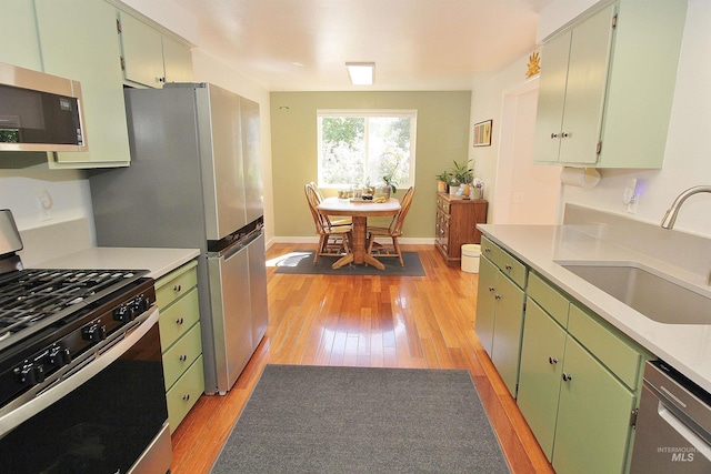2155 N 24th St, Boise, ID 83702 - kitchen with appliances with stainless steel finishes, a sink, light wood finished floors, green cabinets, and light countertops