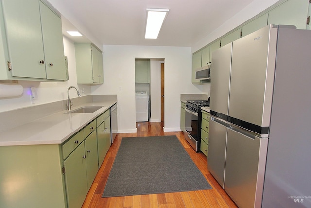 2155 N 24th St, Boise, ID 83702 - kitchen featuring stainless steel appliances, green cabinetry, washer / dryer, a sink, and light wood-style flooring