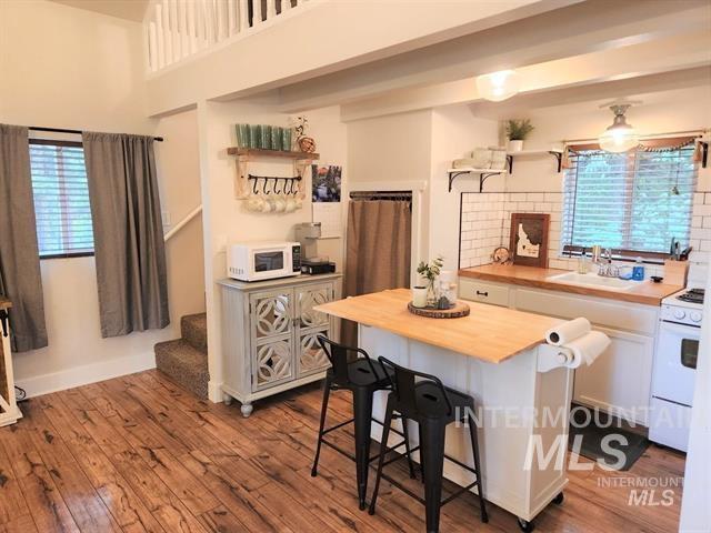 kitchen featuring sink, white appliances, hardwood / wood-style flooring, a breakfast bar, and wood counters