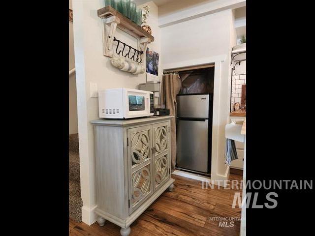 kitchen with dark hardwood / wood-style flooring and stainless steel refrigerator