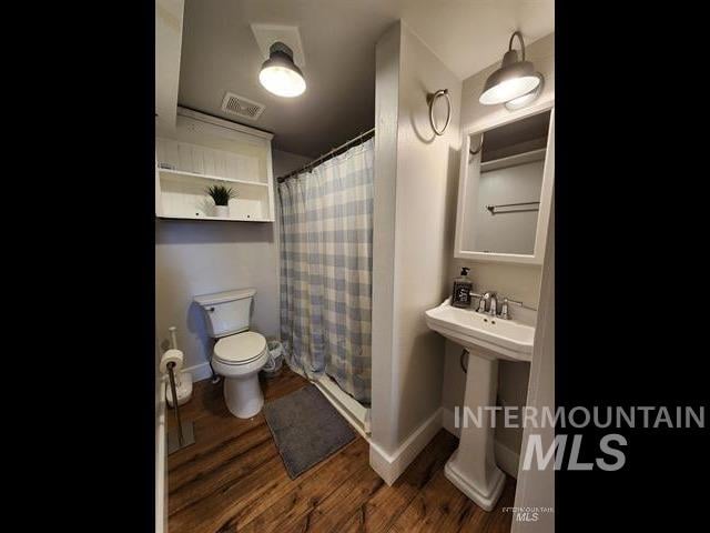 bathroom with walk in shower, hardwood / wood-style floors, and toilet