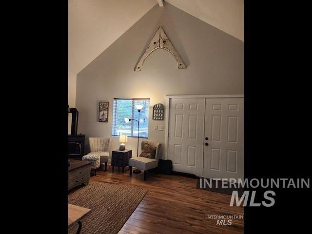 living room featuring hardwood / wood-style flooring, high vaulted ceiling, and a wood stove