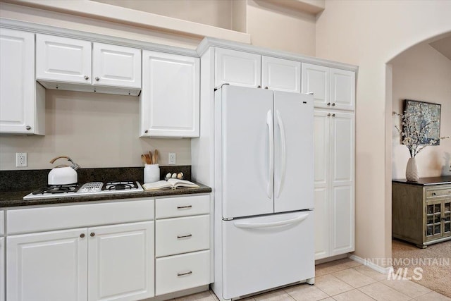 kitchen with white appliances, light tile patterned floors, and white cabinets