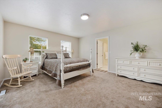 carpeted bedroom with a textured ceiling and connected bathroom